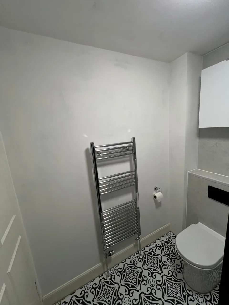 Recessed bathroom shelving beside the toilet and towel rail